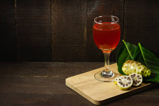 Noni juice and noni fruit with leaf on wooden background. Noni juice and noni fruit with leaf on wooden background. Healthy concept. noni fruit stock pictures, royalty-free photos & images