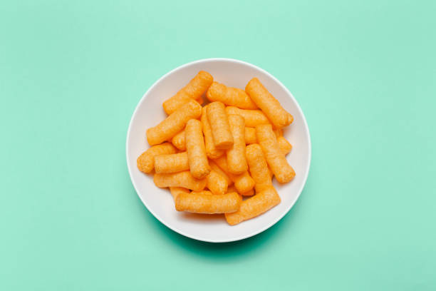 istock Top view of white bowl with corn puffs on green background. 1297773643