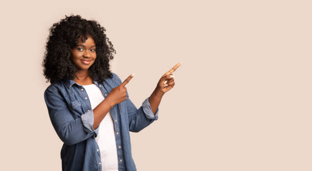 istock Positive black woman pointing at copy space on grey 1297773673