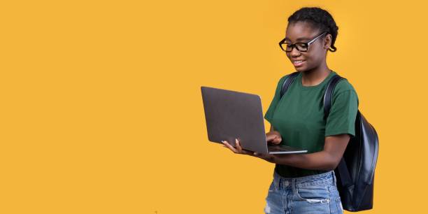 istock Cheerful Black Student Woman Using Laptop Over Yellow Background, Panorama 1297773791