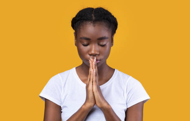 istock Peaceful African Lady Praying Standing With Eyes Closed In Studio 1297773896
