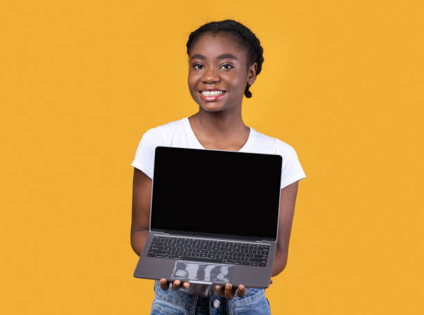 istock Black Lady Showing Laptop Screen Holding Computer On Yellow Background 1297774448
