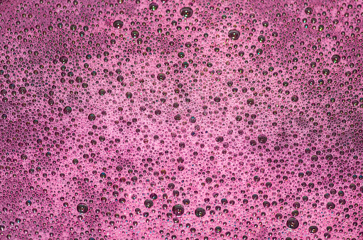 Bubbles on a red wine in the process of natural fermentation of the wort. alcoholic background