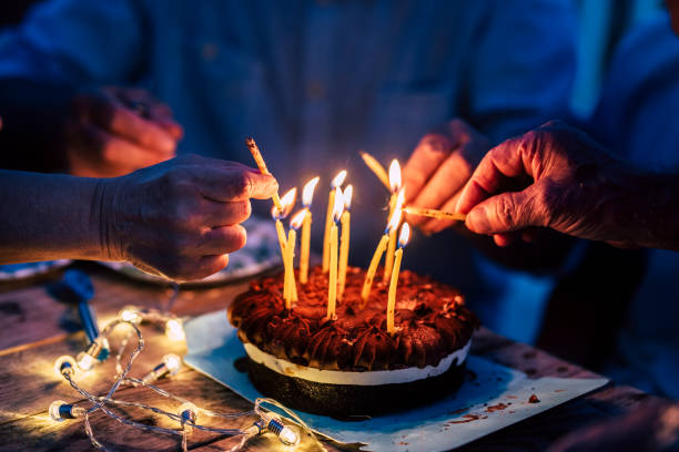 Close up of people hands fire candles on a birthday celebration cake on the table - concept of event and people have fun together in friendship or family leisure Close up of people hands fire candles on a birthday celebration cake on the table - concept of event and people have fun together in friendship or family leisure Ideas for birthdays and anniversaries for seniors stock pictures, royalty-free photos & images