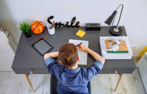 istock Top view of unrecognizable boy doing homework in his bedroom 1297776042