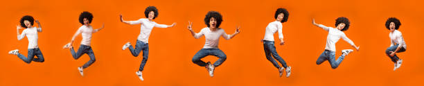 istock Guy Jumping And Having Fun Posing In Mid-Air, Orange Background 1297776335