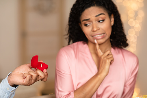 Relationship Breakup Concept. Black man making marriage proposal to young woman rejecting offer, frustrated girlfriend refuse to marry her boyfriend, not taking engagement ring, saying no, thinking