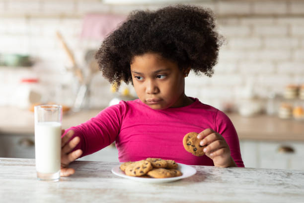 istock Grumpy Little Black Girl Refusing Milk And Eating Cookies In Kitchen 1297777062
