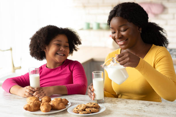 istock Happy Black Mom And Daughter Eating Snacks And Drinking Milk In Kitchen 1297778693