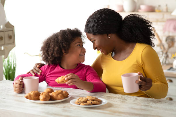 istock Loving Black Mom And Little Daughter Having Snacks In Kitchen At Home 1297778708