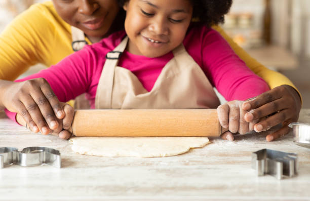 istock Cute Little Girl Learning With Mom How To Roll Dough With Pin 1297778755