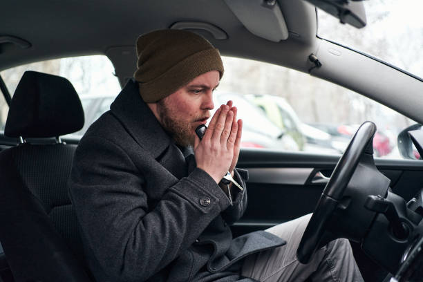 Driver heating his hand in his car so he can a little warm up himself stock photo