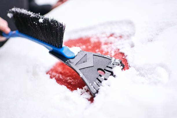 istock Man scraping the snow from his car with plastic ice scraper 1297778998