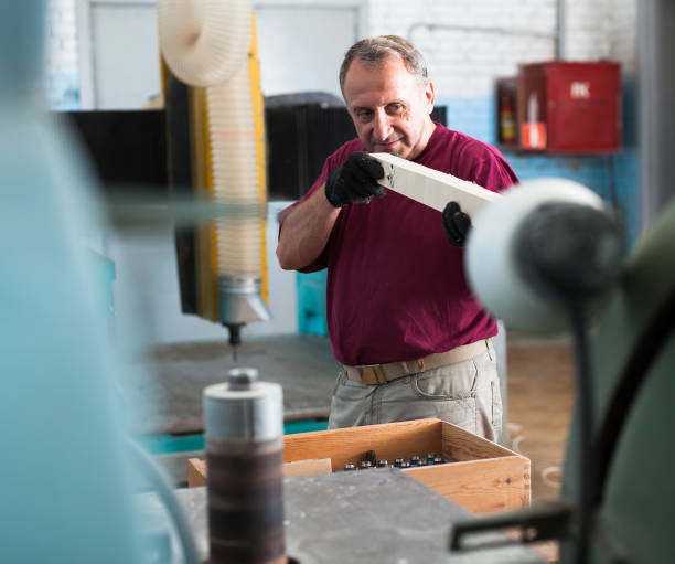 istock Concentrated worker is shaping timber on woodworking machine at the factory 1297779849