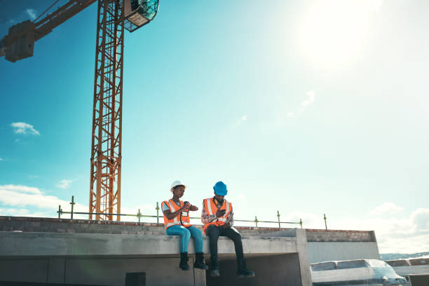 Sun comes out, buildings go up Shot of a young man and woman sitting on top of a building at a construction site construction lunch break stock pictures, royalty-free photos & images