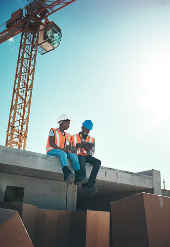 Shot of a young man and woman using a digital tablet on top of a building at a construction site