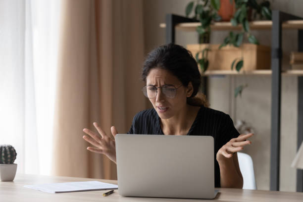 istock Upset young woman confused by laptop problems 1297781582