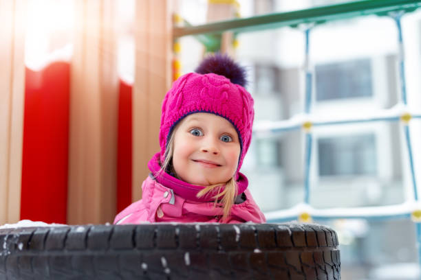 retrato de uma adorável e adorável criança loira feliz e feliz, aproveite para se divertir brincando no jardim de infância ou no quintal no dia de inverno ensolarado e frio. atividades de brincadeiras de crianças fora - playground snow winter little girls - fotografias e filmes do acervo