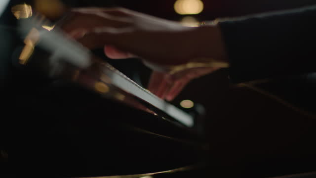 Female pianist plays In Grand Piano On Stage. Black background. Close Up hand.
