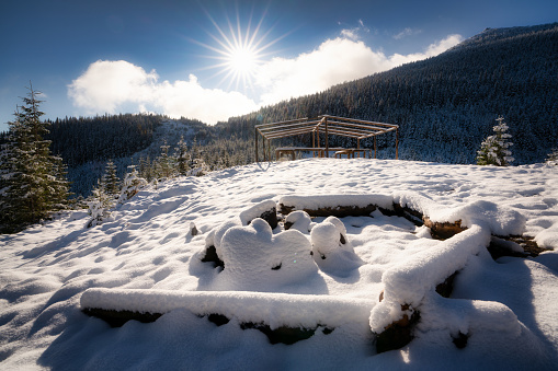 A large snow-covered campfire site for hiking in the Carpathian mountains I bright cold sun