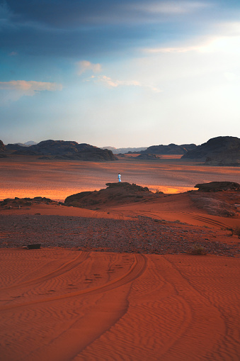 The bedouin dressed in white observes the boundless grandeur of the Jordanian desert. The Wadi Rum.