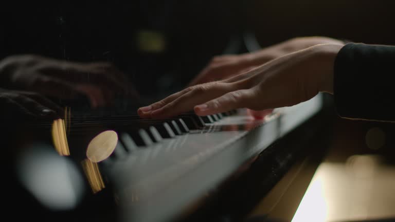 Female pianist plays In Grand Piano On Stage. Black background. Close Up hand.