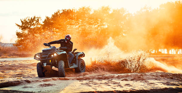 Cross-country quad bike race, extreme sports Teen riding ATV in sand dunes making a turn in the sand quadbike photos stock pictures, royalty-free photos & images