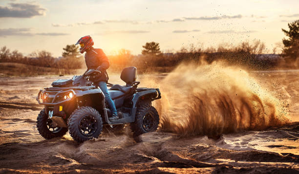 Cross-country quad bike race, extreme sports Teen riding ATV in sand dunes making a turn in the sand quadbike photos stock pictures, royalty-free photos & images