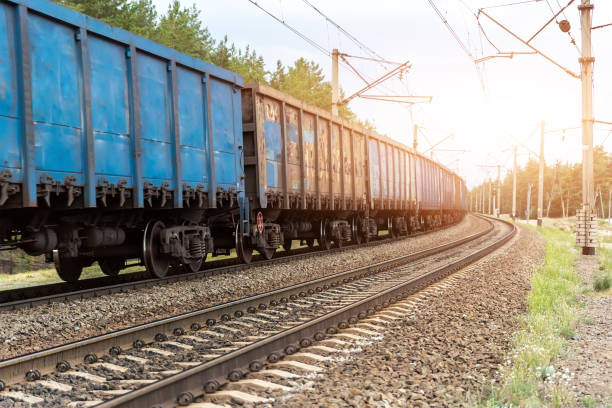 istock Motion blurred heavy cargo freight rusty train wagons moving on railway on sunset or sunrise day time. Industrial materials transportation and goods delivery concept. Old rusty wagons moving by rail 1297789955