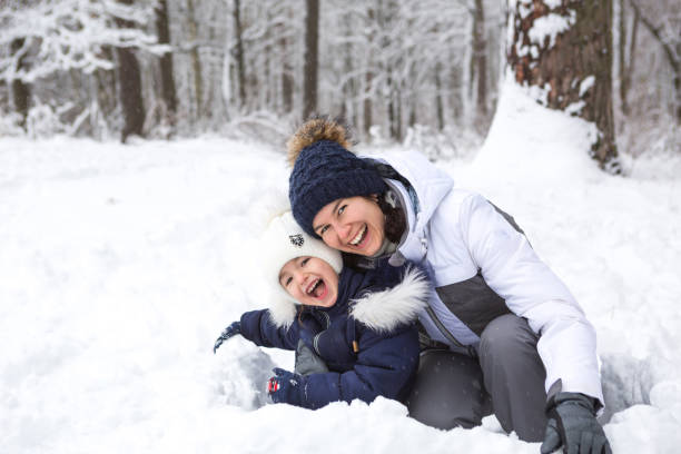 Mom and daughter play snow games, build a fortress, make snowballs. Winter entertainment outside, active recreation, fun in the cold in warm clothes. Outdoor recreation, fun childhood, strong family mamá e hija juegan juegos de nieve, construyen una fortaleza, hacen bolas de nieve. entretenimiento de invierno al aire libre, recreación activa, diversión en el frío en ropa de abrigo. recreación al aire libre, infancia divertida, familia fuerte