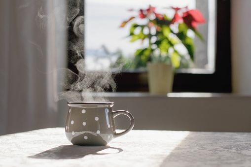 Cup of hot tea on the table, cozy home interior background