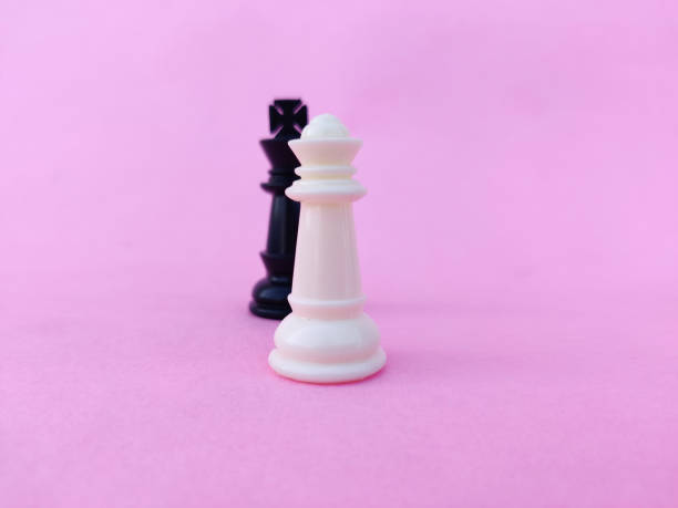 istock White chess queen and black chess king facing each other. Isolated on pink background 1297795228