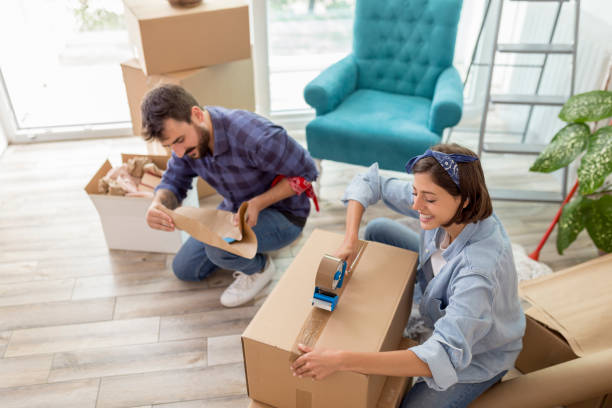 istock Couple packing things in cardboard boxes while moving house 1297799204