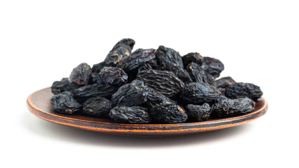 istock Dark blue raisins on a plate isolated on white background 1297800194