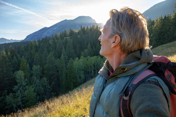 istock Male hiker walks along forested trail at sunrise 1297800299