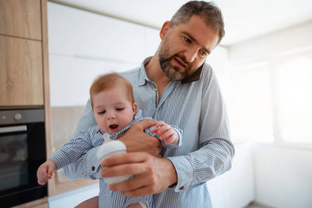 istock Man preparing a meal for baby boy while on phone working from home 1297800759