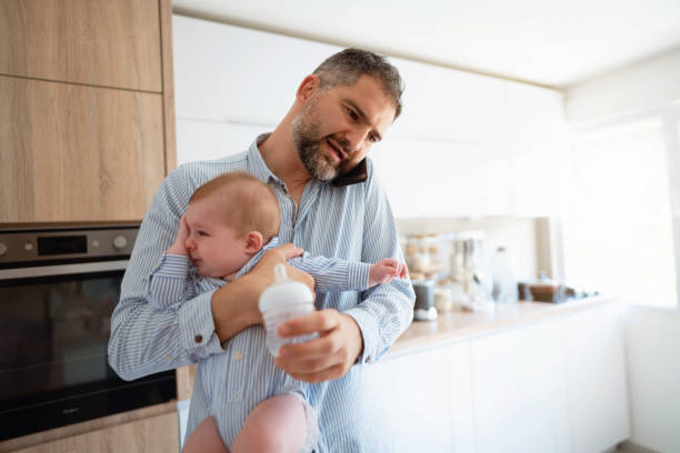 istock Working father talking on the phone while preparing a meal to his cute baby boy 1297800772