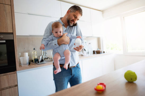 istock Man holding his son while on phone working from home 1297800823
