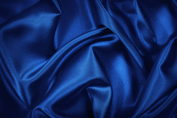 istock Luxurious blue silk satin background. Soft wavy folds on shiny fabric. Beautiful abstract background with copy space for design. 1297801866