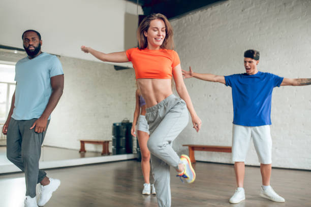 istock Long-haired girl with raised leg and friends in studio 1297804441