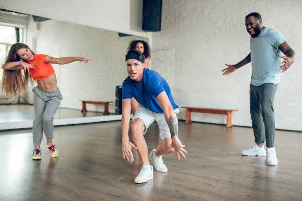 istock Cheerful guy with tattoo and friends dancing in studio 1297804451