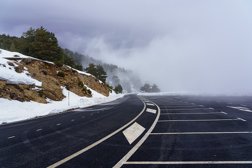 Mountain road with snow and fog on sunny day.\nMorcuera Madrid.