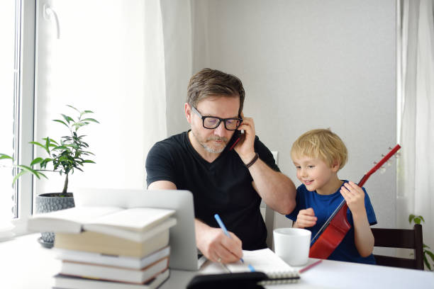 istock Man working from home with laptop during quarantine. Home office and parenthood at same time. Exhausted parent with hyperactive child. 1297805811