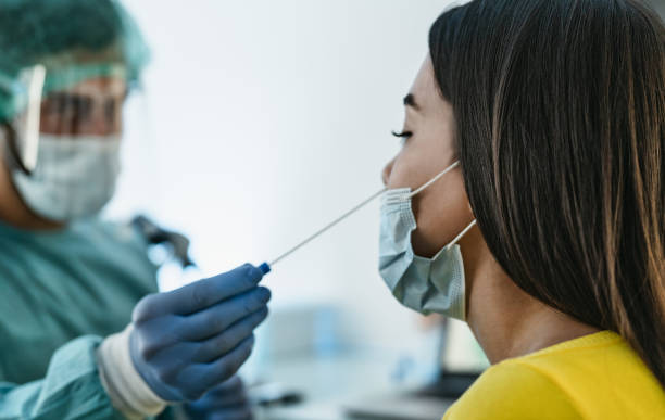 여성 환자에 코로나 바이러스 면봉을하고 개인 보호 장비를 착용 의료 종사자 - covid19 테스트 및 건강 관리 개념 - covid 뉴스 사진 이미지