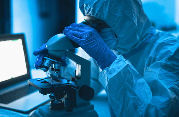 istock Young scientist working in laboratory examining coronavirus through microscope - Science and technology concept 1297810893