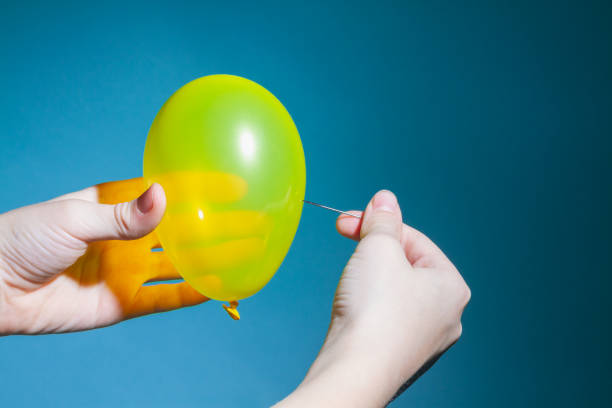 istock Pierce or pop a yellow balloon with a needle on a blue background 1297812491