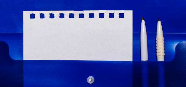 istock On a blue background, white pens and a sheet of paper to insert text 1297813171