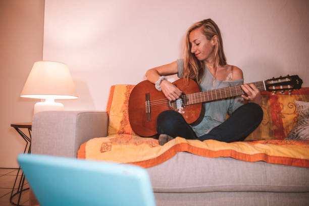 istock Woman learns guitar online from digital tablet 1297814613