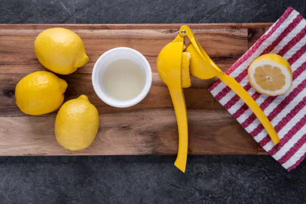 Sliced lemons being freshly squeezed on a cutting board with a kitchen towel