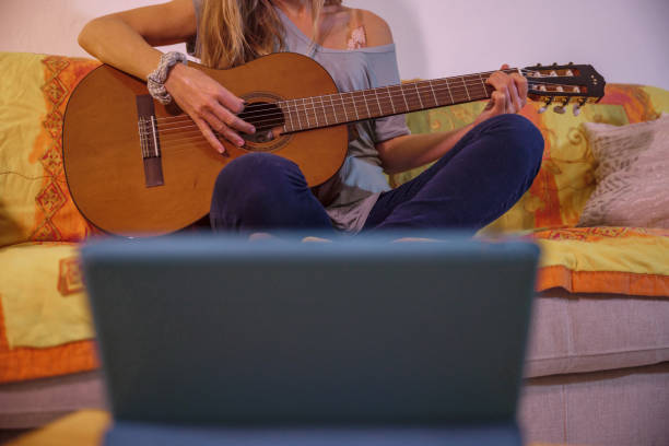 istock Woman learns guitar online from digital tablet 1297814628